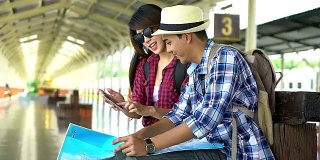 一对年轻的旅行者在火车站边看地图边讨论他们的旅行。