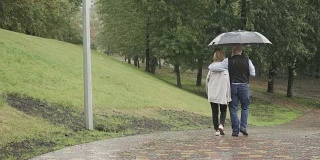 恋爱中的人在公园的伞下散步