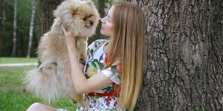 一个女孩和一只狗在公园散步。波美拉尼亚的猎犬
