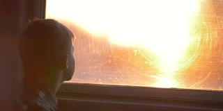 男孩晚上乘火车望着窗外，阳光灿烂