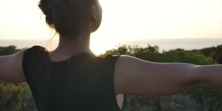 一个年轻女子站在岛上的悬崖上望着大海