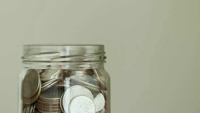 硬币落入玻璃罐，省钱，捐赠或企业财务增长概念，4K Dci分辨率