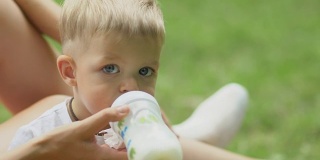 小男孩用婴儿奶瓶喝牛奶
