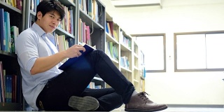 亚洲男大学生在图书馆地板上看书做研究。