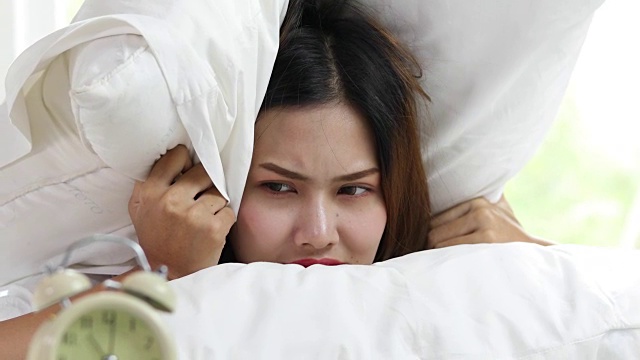 闹钟有一个美好的一天亚洲妇女醒来在她的床上充分休息，打开窗帘在早上得到新鲜空气。