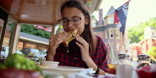 在宾夕法尼亚州波科诺斯地区的吉姆·索普，一个16岁的漂亮女孩在街上的咖啡馆里吃着三明治