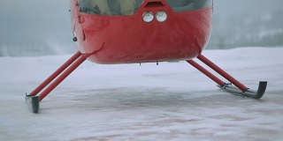 一架红色的直升机在白雪覆盖的田野上起飞。