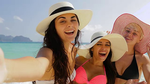 在海滩上用手机自拍的女孩，快乐的穿着比基尼和草帽的女人在暑假