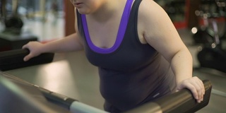 不健康的超重妇女因在跑步机上锻炼，行走缓慢而疲惫不堪