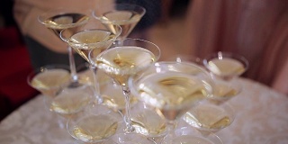 宴会上，客人们的手拿着盛着冒泡葡萄酒的玻璃杯。金字塔里有玻璃。没有可识别的个人
