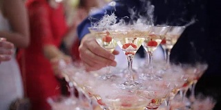 宴会上，客人们的手拿着盛着冒泡葡萄酒的玻璃杯。金字塔里有玻璃。没有可识别的个人