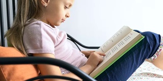 小女生在家里指着课本慢慢地读着