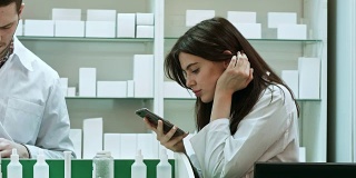 无聊的女药剂师在药房使用手机