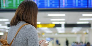 一名女乘客在离港机场办理登机手续前，用手机在数字登机牌上检查她的航班