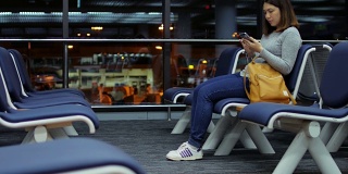 一名女子乘客在夜航离港机场触摸手机