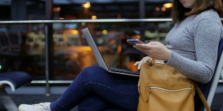 一名女子乘客在夜航离港机场触摸手机和使用笔记本电脑