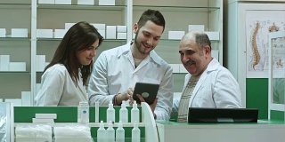 一男一女，两男一女，笑容满面地站在药房的平板电脑上查看信息