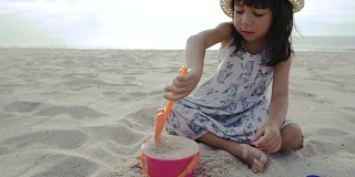 一个小女孩在沙滩上用铲子和水桶玩沙子