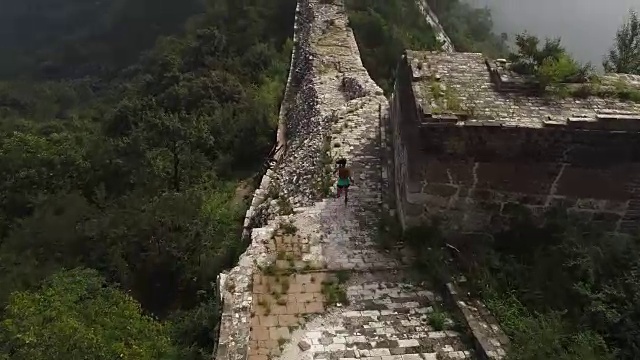 鸟瞰图的年轻的健身妇女越野跑跑在长城的顶端