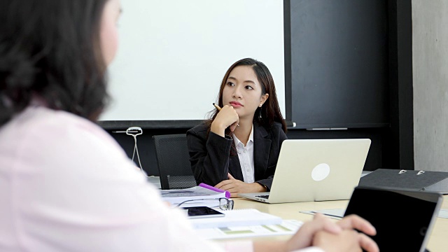 亚洲商人和团队工程师在会议上用笔记本给商业伙伴讨论文件和想法，商务女性在工作中微笑