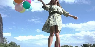 一个美丽的女孩在户外拿着一个气球，背景是山脉和河流。想想亚洲女孩的开朗。