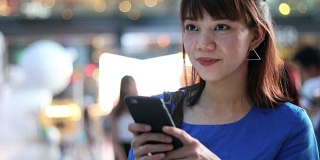 一名中国妇女在夜城的街道上使用手机