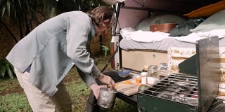 帅气的年轻人把食物放进野营锅里，在野营时做饭