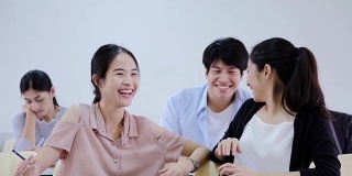 十几岁的亚洲人在学校里，一群大学生在大学教室里谈话。