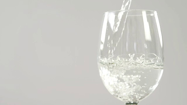 白葡萄酒在白色背景下落在玻璃杯中