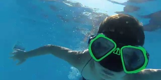 男孩在游泳池里潜水，看着相机，水下拍摄，阳光