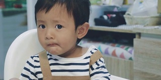 亚洲男婴在高椅子上吃东西。
