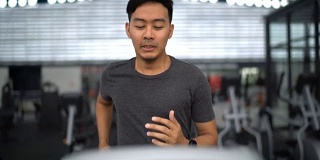 正面视图的亚洲人在跑步机上在健身房