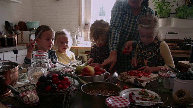 年轻的家庭准备自制浆果果酱和罐装在罐子里