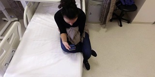女性患者手术后在医院病床上使用智能手机等待出院
