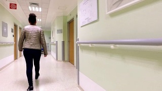 年轻的女病人走在医院的走廊上视频素材模板下载