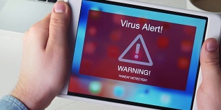 男子手持数字平板电脑，屏幕上有病毒警报警告标志