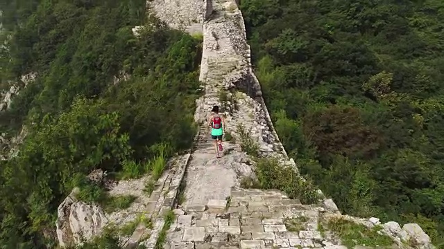 鸟瞰图的年轻的健身妇女越野跑跑在长城的顶端