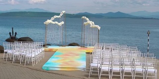 海边的婚礼拱门，前面是一排排的椅子。