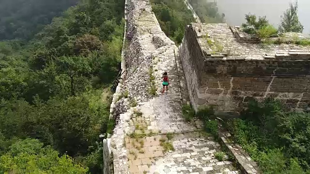 鸟瞰图的年轻的健身妇女越野跑跑在长城的顶端