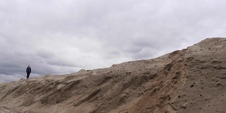 身材苗条的专心慢跑女子正在沙漠中跑步。背景是乌云密布