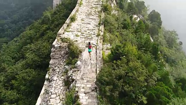 鸟瞰图的年轻的健身妇女越野跑跑在长城的顶端