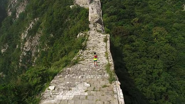 鸟瞰图的年轻的健身妇女越野跑跑在长城的顶端