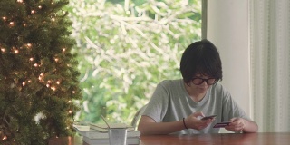 一个年轻的亚洲女人用手机在家里用信用卡下单。