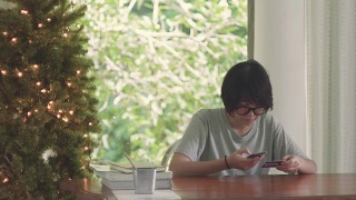 一个年轻的亚洲女人用手机在家里用信用卡下单。视频素材模板下载