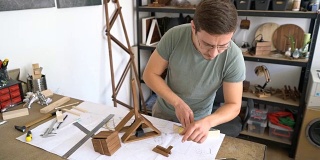 年轻人测量和组装木制部件为他的工艺项目