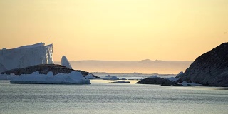 北冰洋上的冰山与格陵兰岛的日落