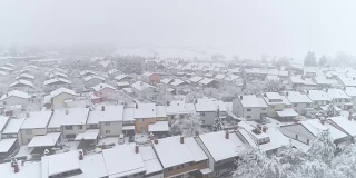 鸟瞰图:冬日里，在宁静的郊区城市里，飞翔在白雪覆盖的房屋上方