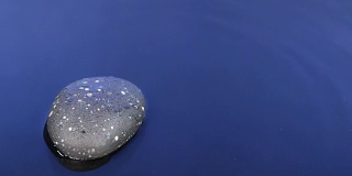 落一滴水在黑色的石头和蓝色的水