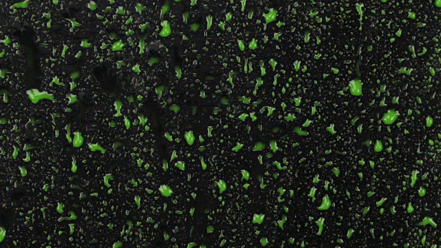 几滴绿色的颜料滴在黑色的背景上，就像小溪一样