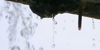 慢镜头:近距离观察，水滴从屋檐落下